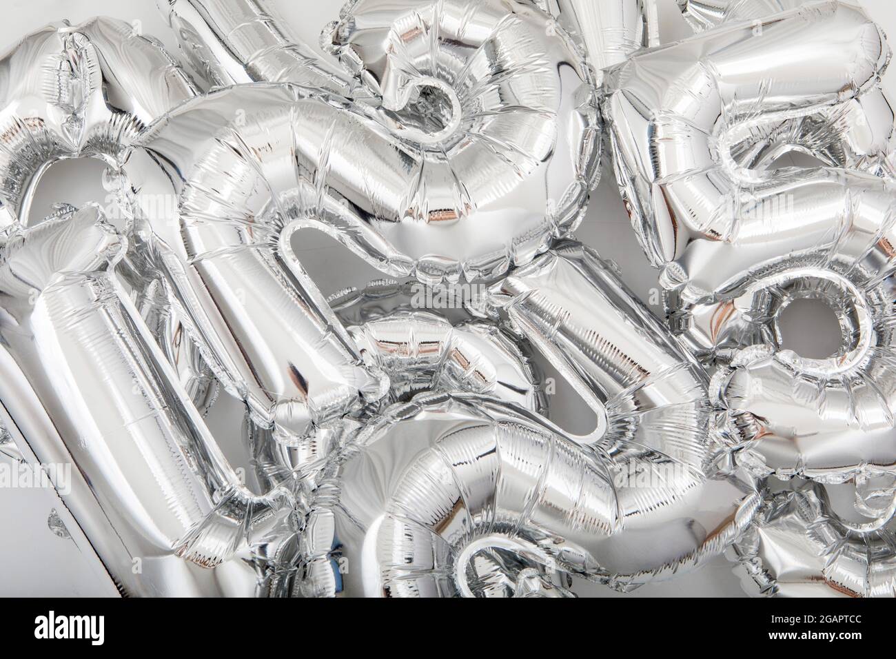 Dall'alto di sfondo full frame di vari palloncini numero argento sparsi su tavolo bianco Foto Stock