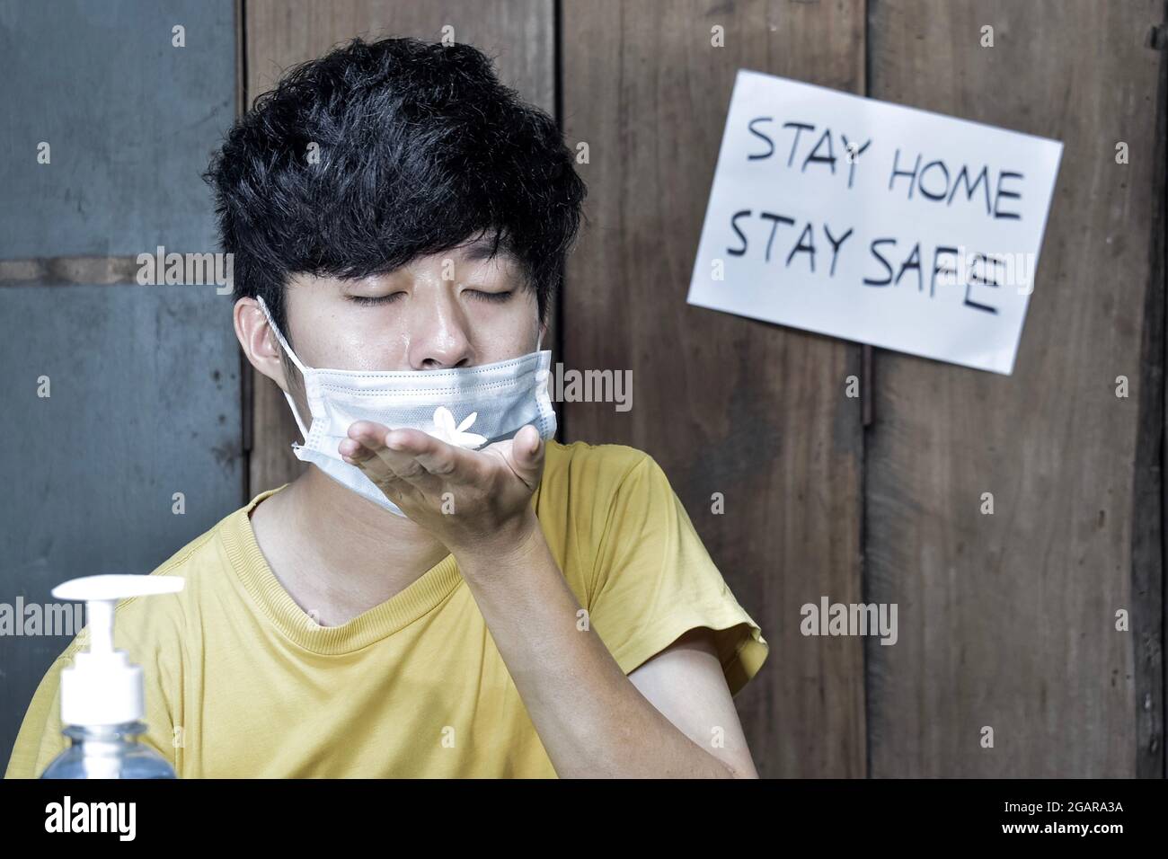 Sud-est asiatico, cinese e Myanmar giovane uomo con influenza fredda ottiene la perdita di odore chiamato anosmia. Indossa una maschera chirurgica e odori di flo di gelsomino Foto Stock