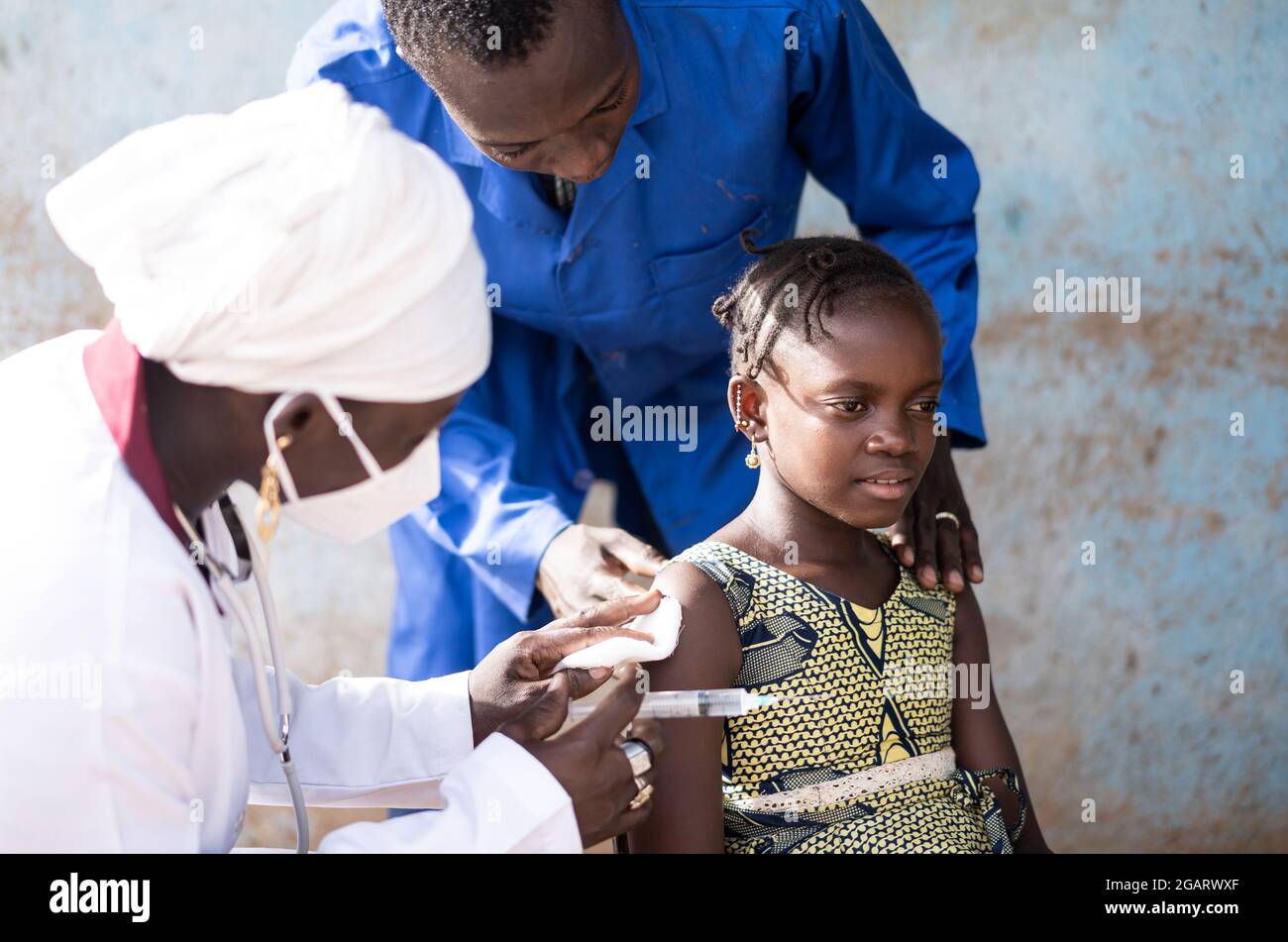 In questa immagine, una bambina africana alleviato è curata dal personale di vaccinazione dopo che ha ricevuto il suo primo colpo di Covid Foto Stock