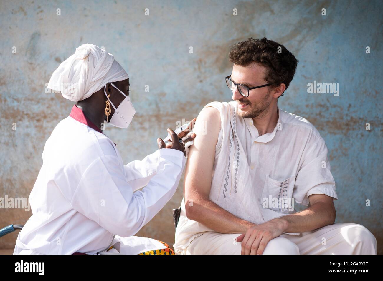 In questa immagine, un'operatrice sanitaria caucasica bianca contenuto sta receving un vaccino sparato da un medico nero femmina durante la prevenzione di malattie infettive in Foto Stock