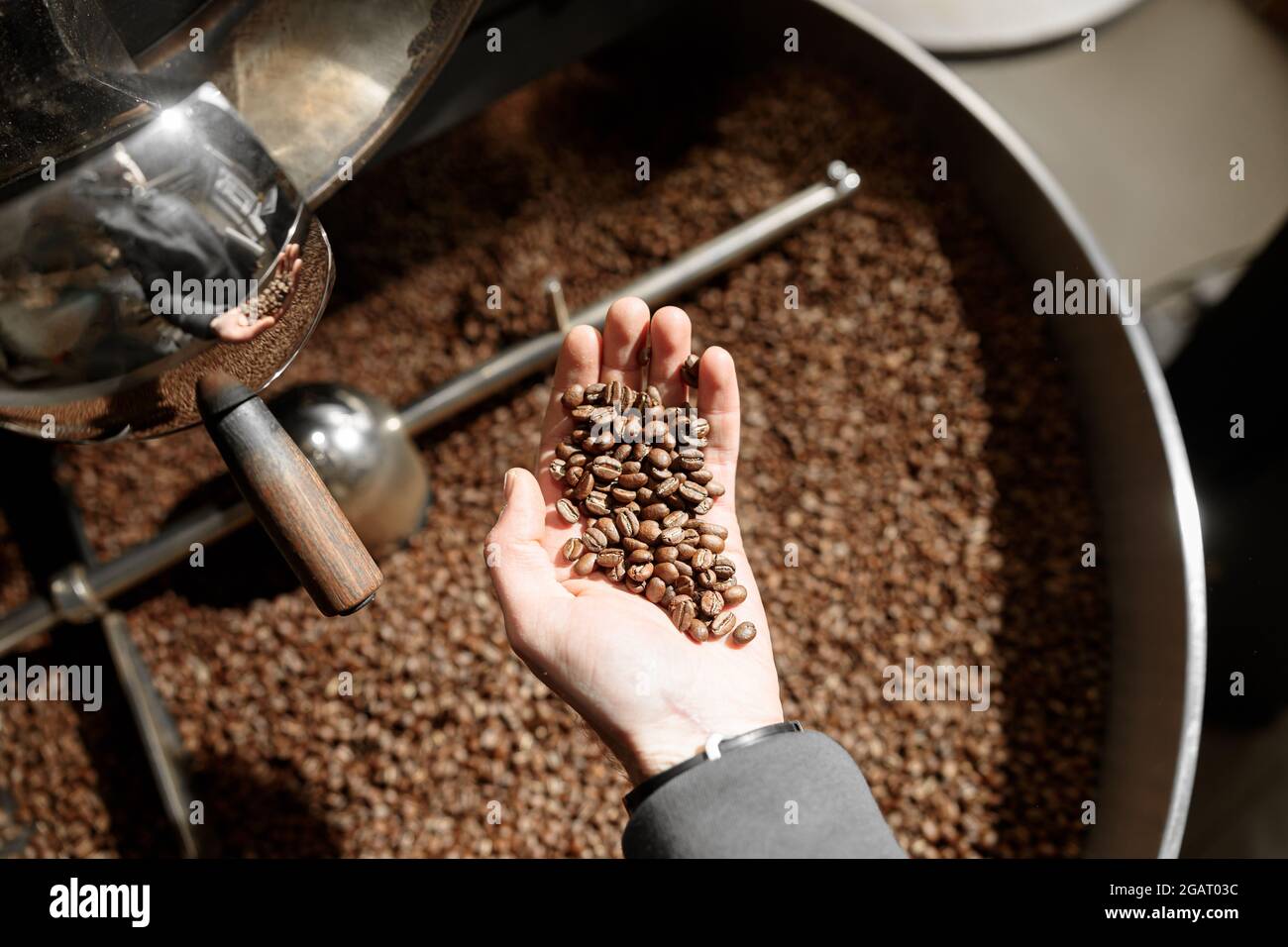 Un giovane lavoratore specializzato sta arrostendo il caffè nell'hangar Foto Stock