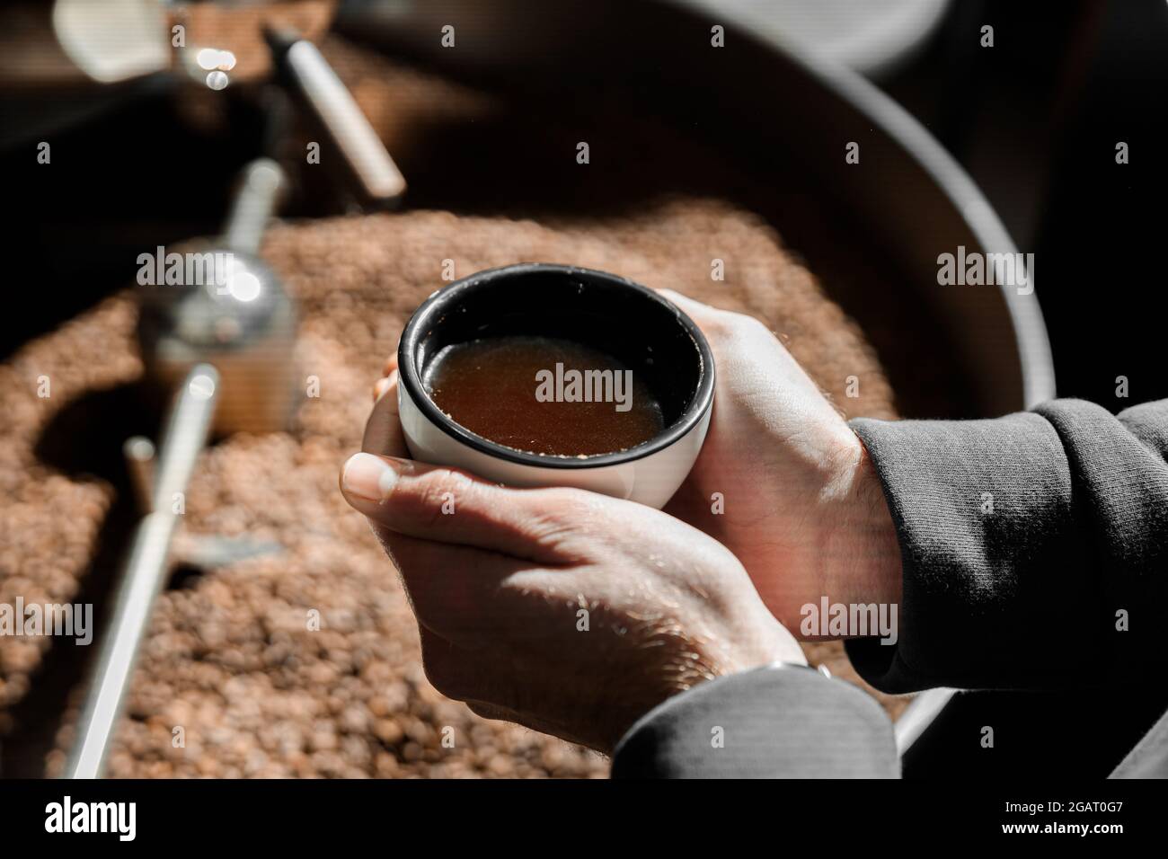 Un giovane lavoratore specializzato sta arrostendo il caffè nell'hangar Foto Stock