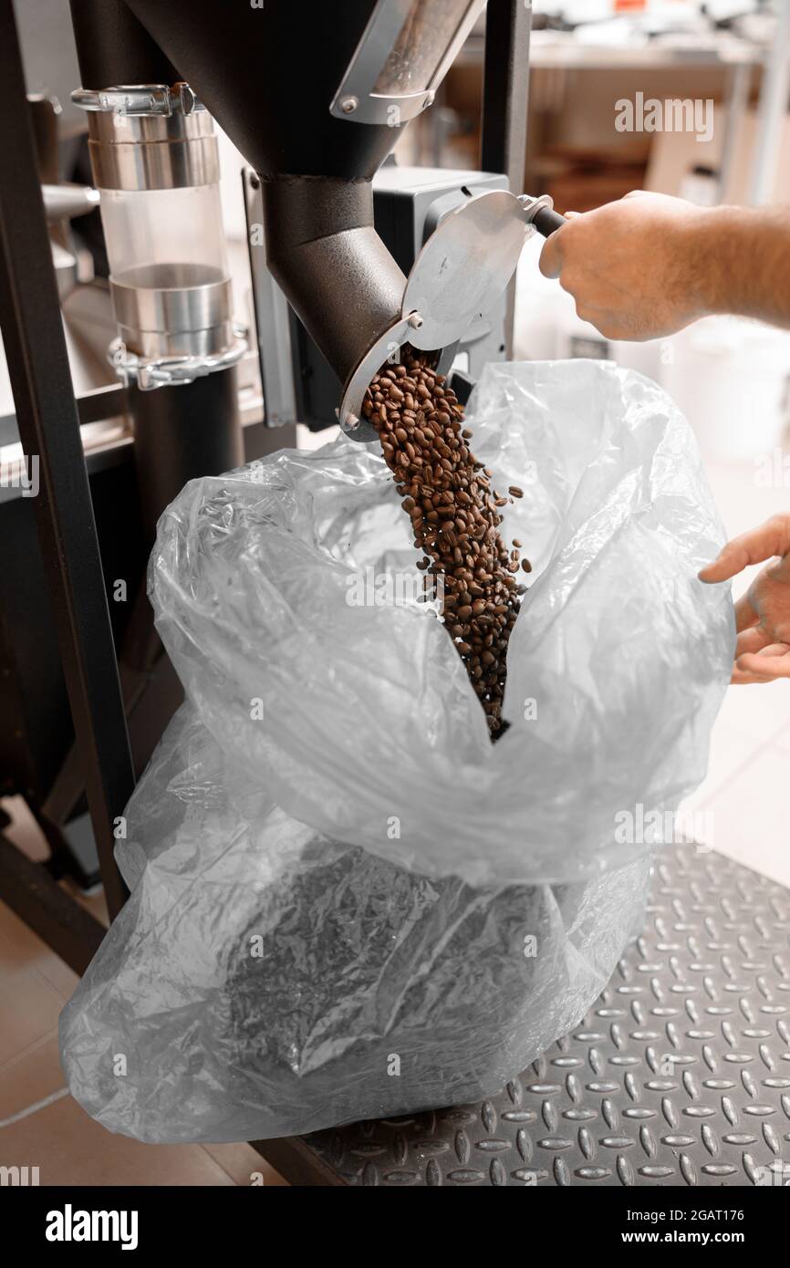 Un giovane lavoratore specializzato sta arrostendo il caffè nell'hangar Foto Stock