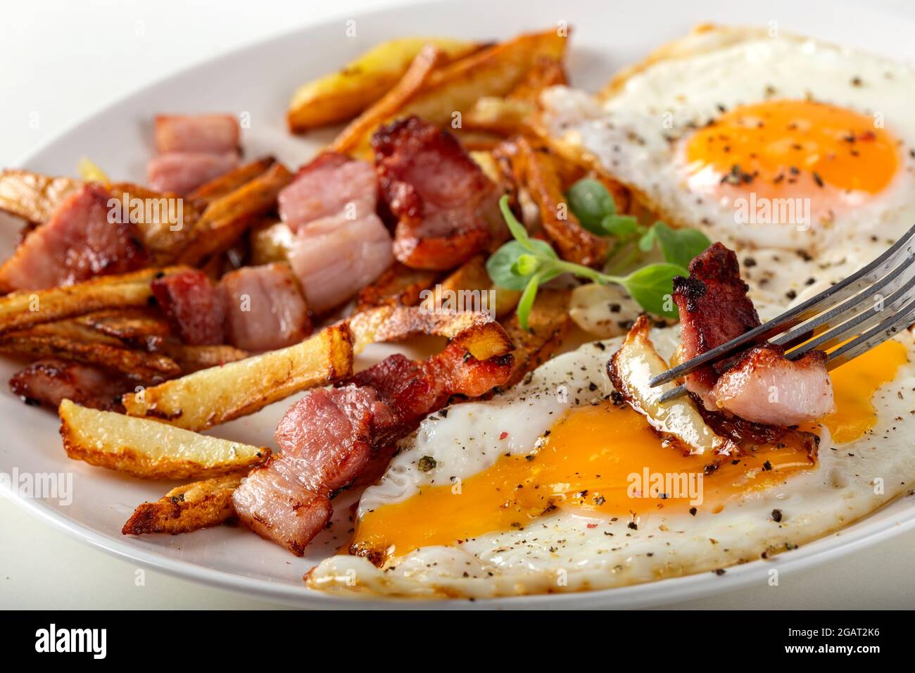 Mangiare patatine fritte con uova fritte e pancetta - vista ravvicinata Foto Stock