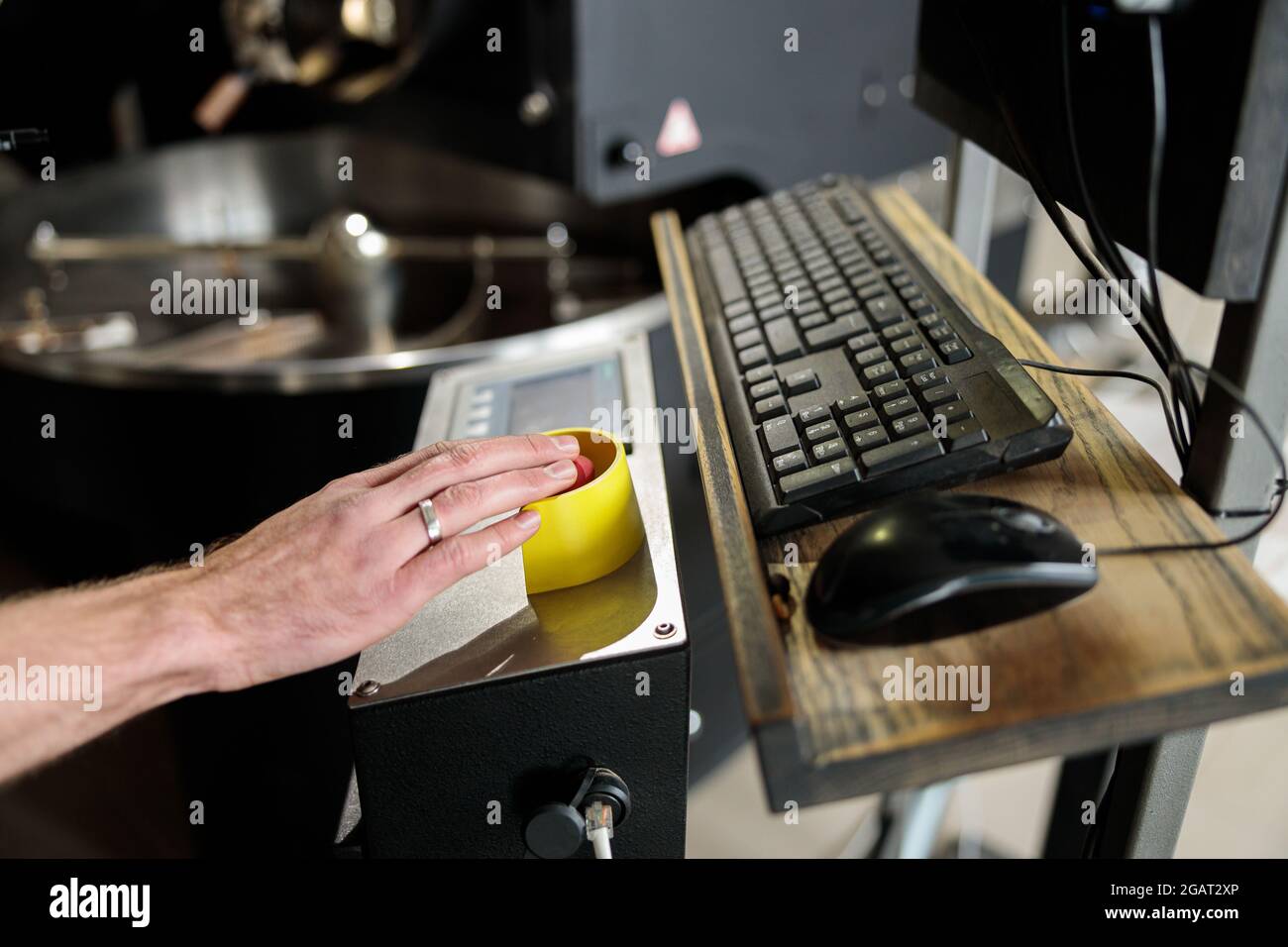 Un giovane lavoratore specializzato sta arrostendo il caffè nell'hangar Foto Stock