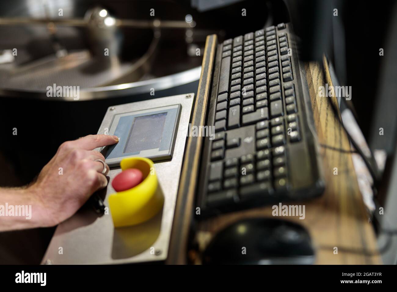 Un giovane lavoratore specializzato sta arrostendo il caffè nell'hangar Foto Stock