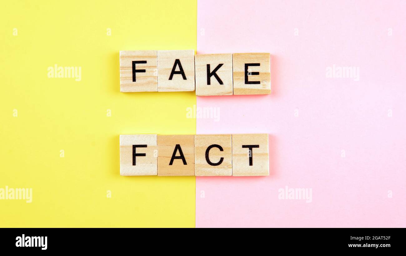Un tessere di parola che forma il fatto di parola e falso su uno sfondo giallo e rosa. Fuoco selettivo sulla parola falso e sul fatto. Foto Stock