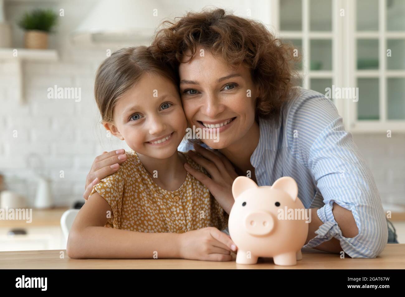 Testa ha girato ritratto la bambina e la madre con la banca del piggy Foto Stock