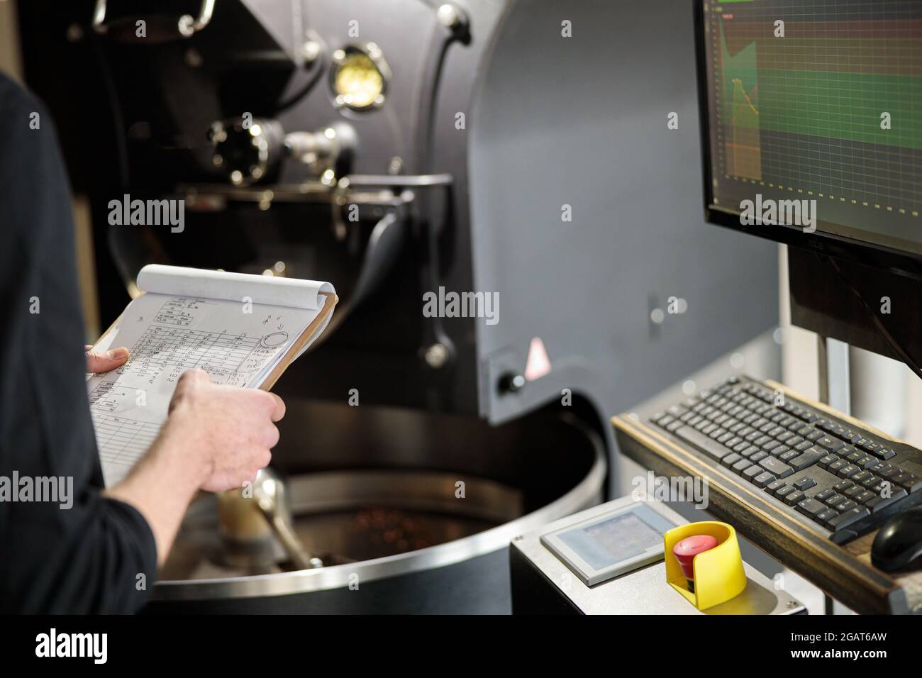 Un giovane lavoratore specializzato sta arrostendo il caffè nell'hangar Foto Stock