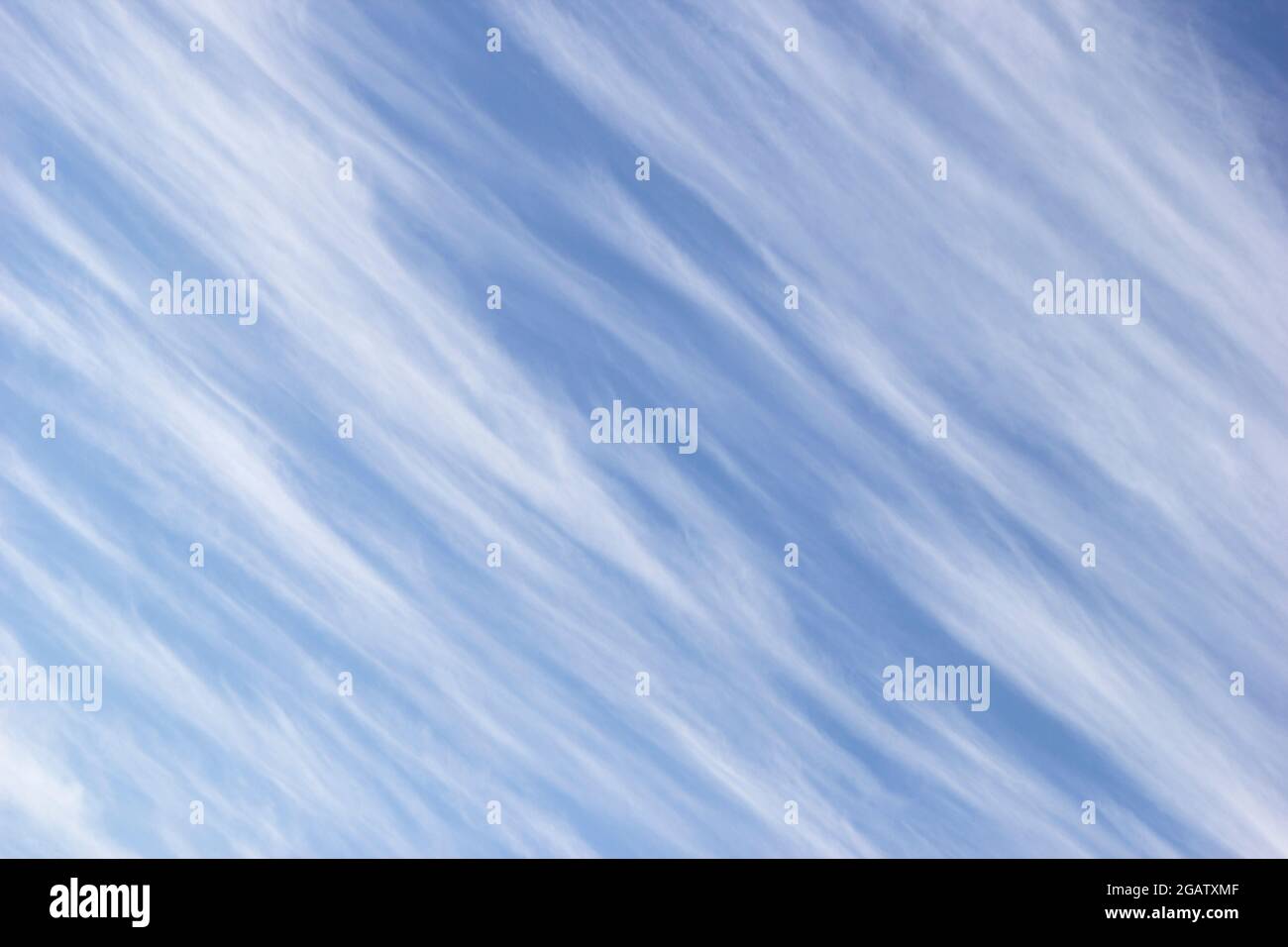 Nuvole di cirrus bianco sotto forma di strisce diagonali sullo sfondo blu cielo. Foto Stock