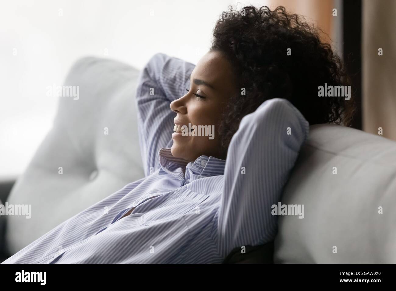 Donna afro-americana felice rilassarsi su divano daydreaming Foto Stock