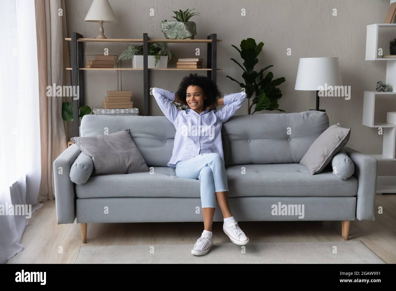 Sorridente biracial donna rilassarsi sul divano a casa Foto Stock
