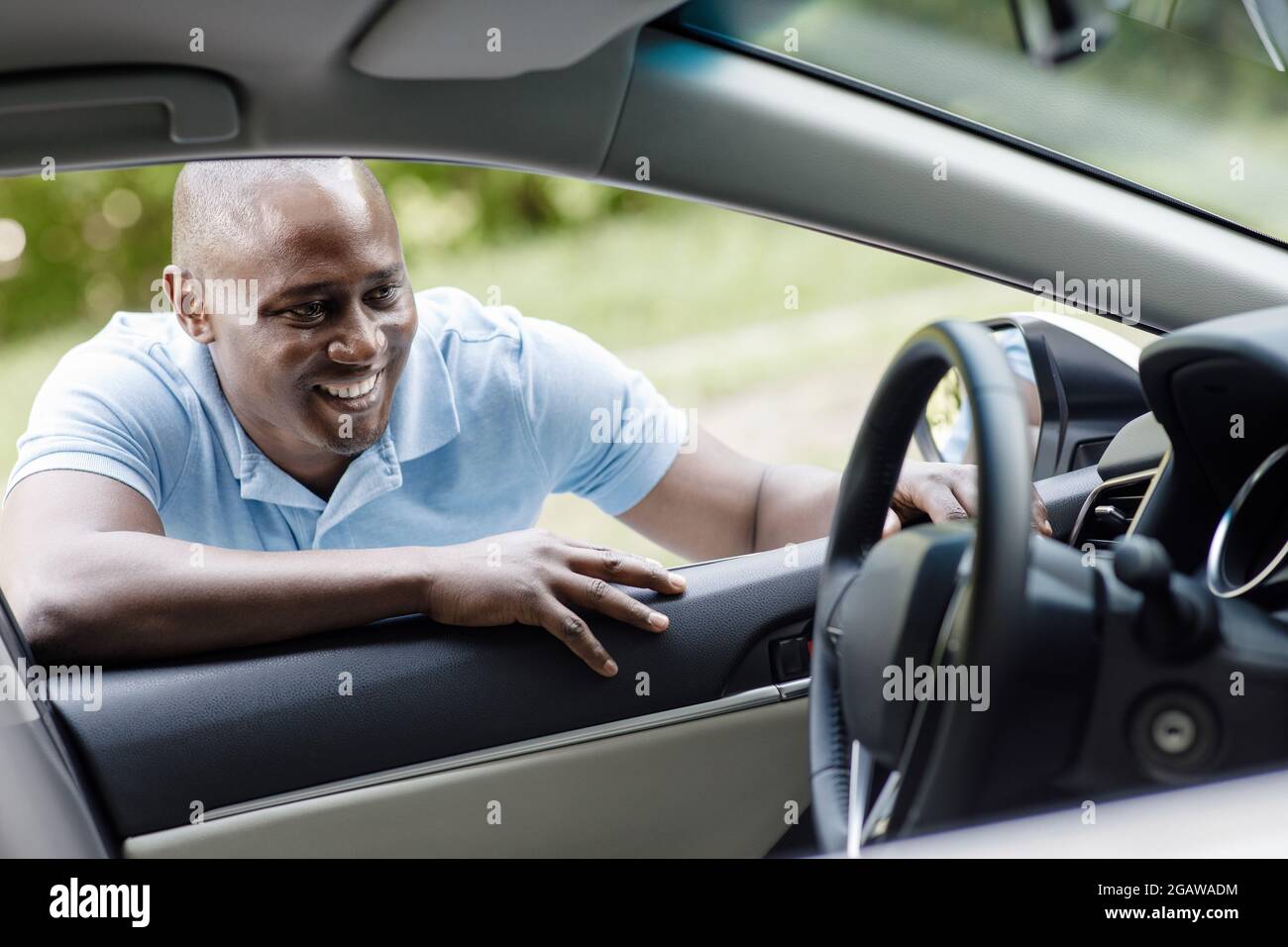 Felice cliente africano americano uomo che guarda all'interno di nuova auto, controllare le automobili per le esigenze quotidiane, allegro ragazzo nero che va comprare auto, outdo in piedi Foto Stock