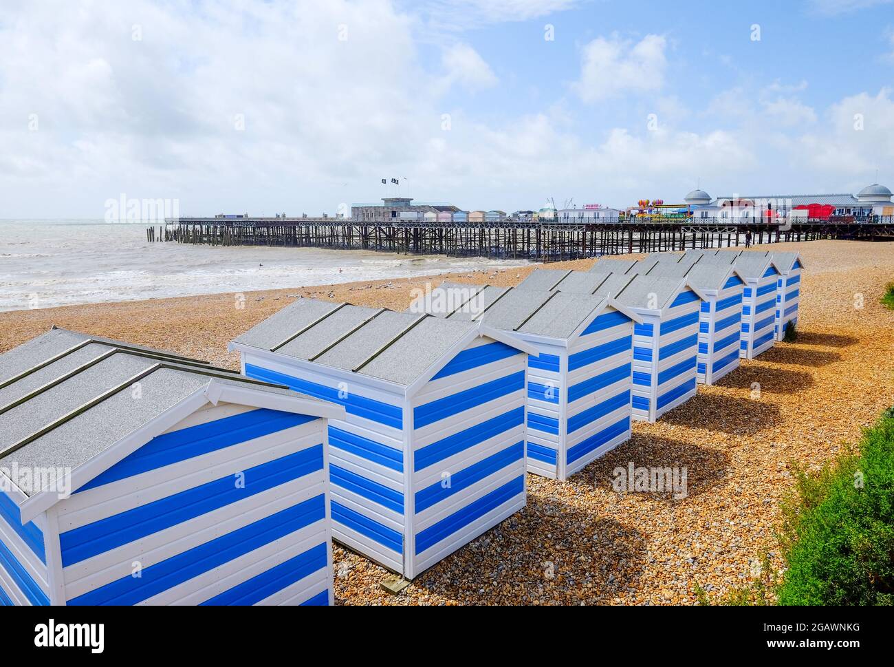 Hastings Pier e capanne sulla spiaggia di Hastlings Beach, Hastling, East Sussex, Regno Unito Foto Stock