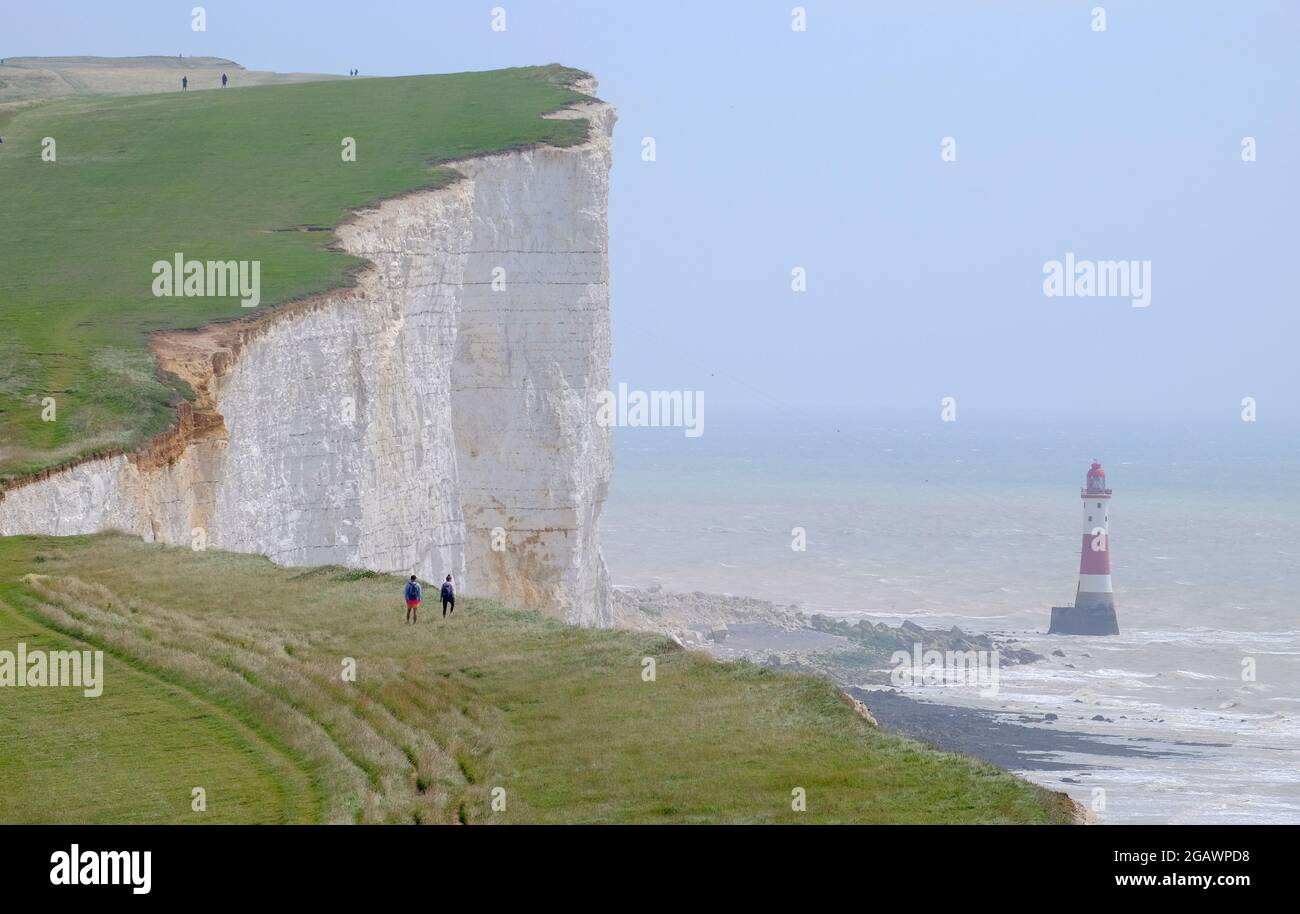 Camminatori sulla South Downs Way passando il faro a Beachy Head, East Sussex, UK Foto Stock