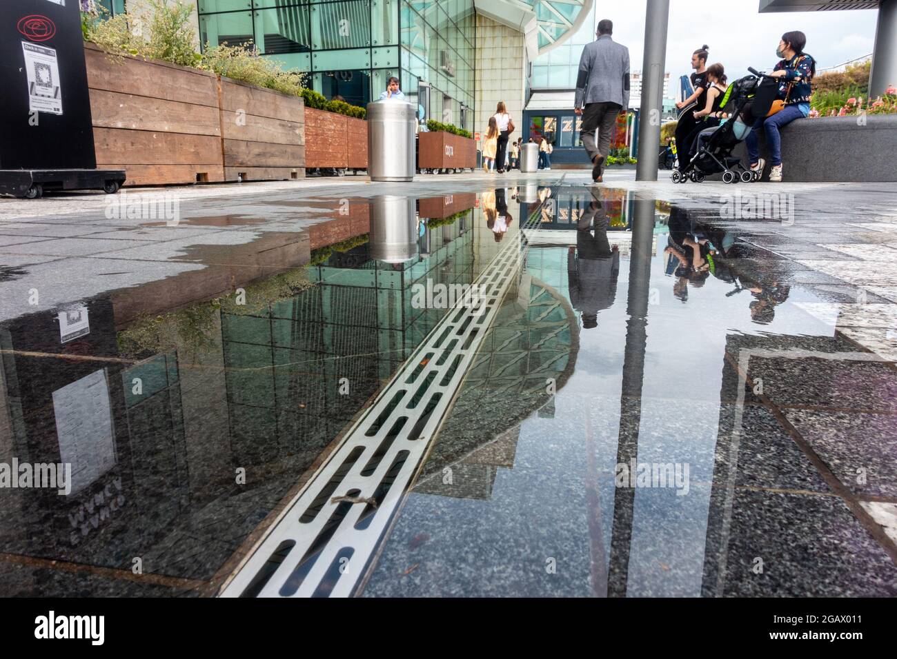 Riflessioni in un pozze in un centro commerciale affollato. Foto Stock