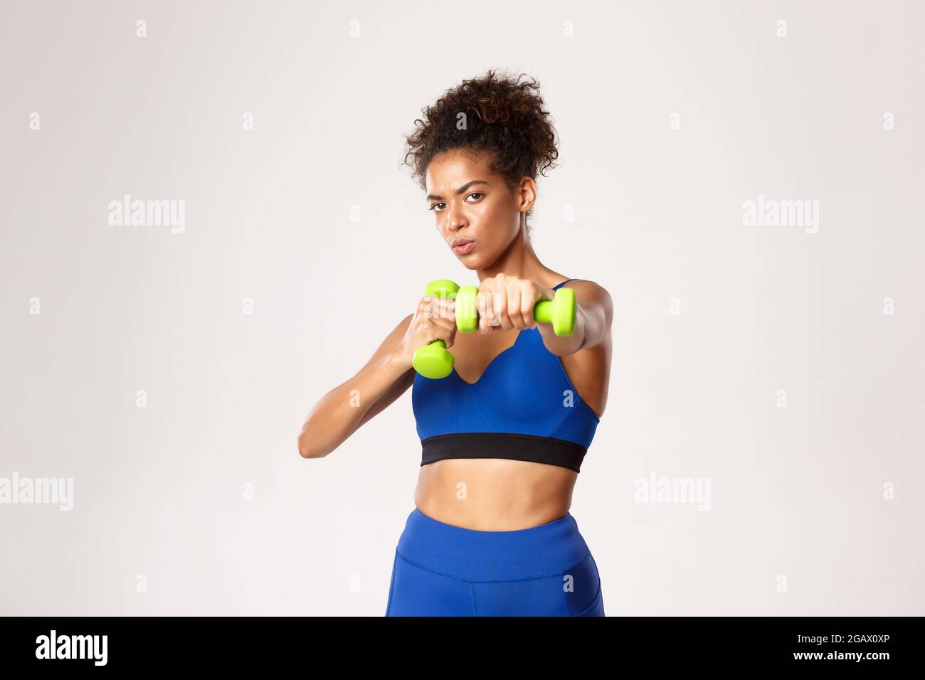 Concetto di sport e allenamento. Determinata afroamericana donna fitness,  pugilato, pugni di pratica con manubri, in piedi su sfondo bianco Foto  stock - Alamy