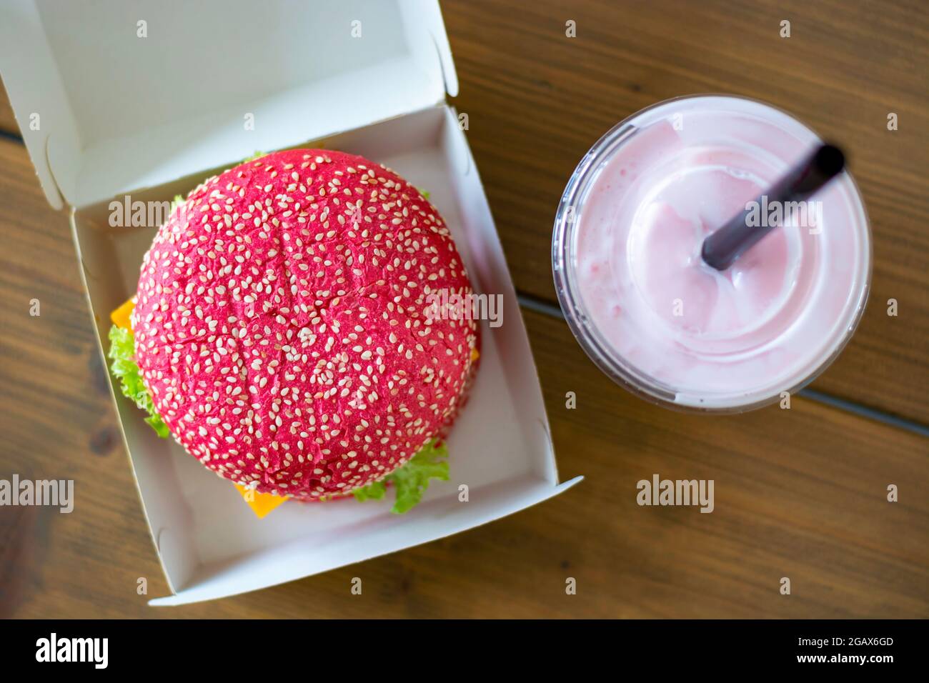 Panino di hamburger rosa senza glutine di barbabietole con hamburger vegetariano, con frullato rosa. Hamburger sano alternativo. Cibo alla moda. Vista dall'alto. Foto Stock