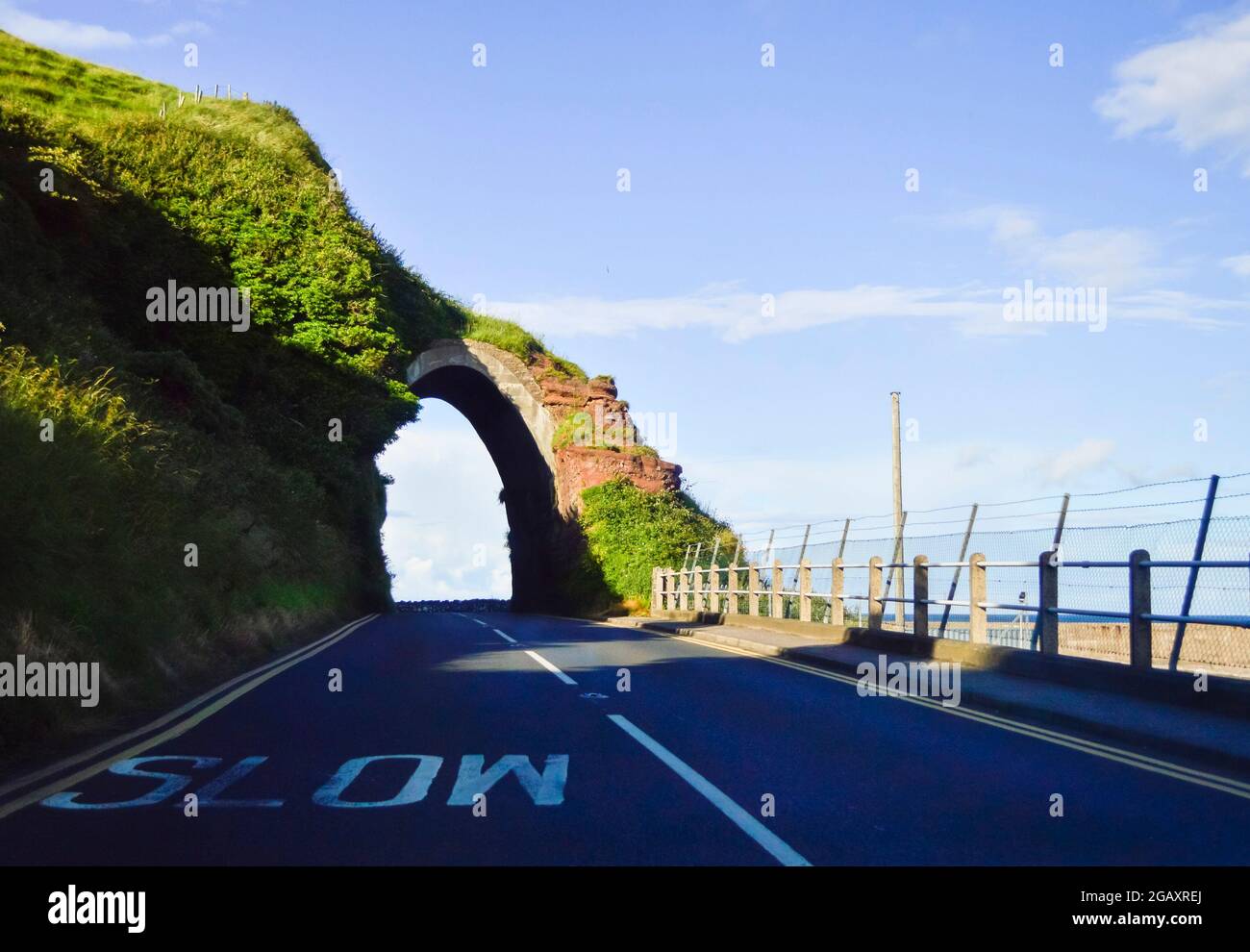 Un vialetto con arco lungo la costa del Selciato dei Giganti dell'Irlanda del Nord. Foto Stock