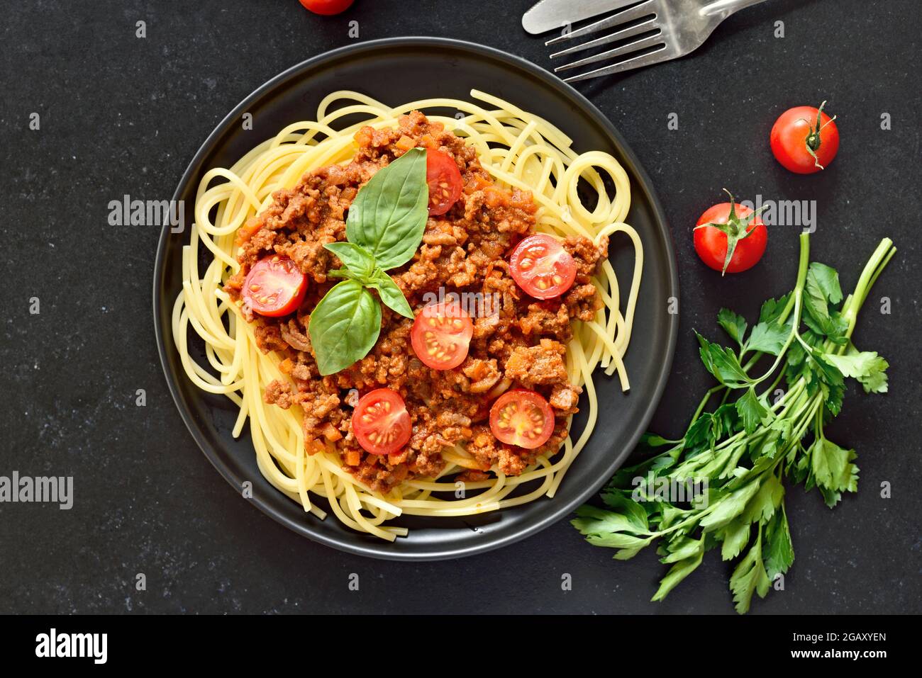 Spaghetti bolognesi italiani su piatto su fondo di pietra nera. Vista dall'alto, disposizione piatta Foto Stock