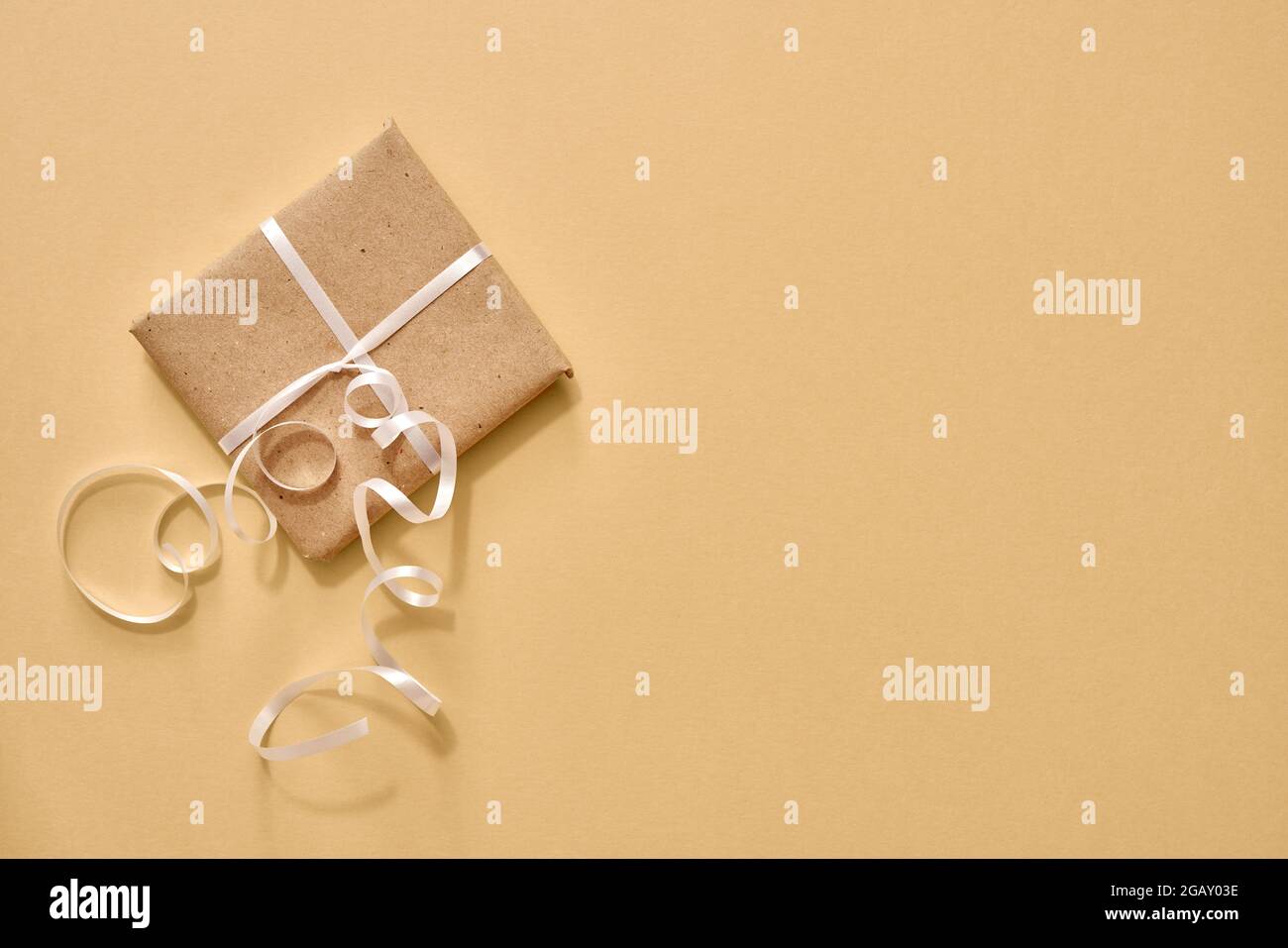Regalo di Natale avvolto in carta riciclata ecologica su sfondo pastello con copia spazio - zero rifiuti concetto Foto Stock