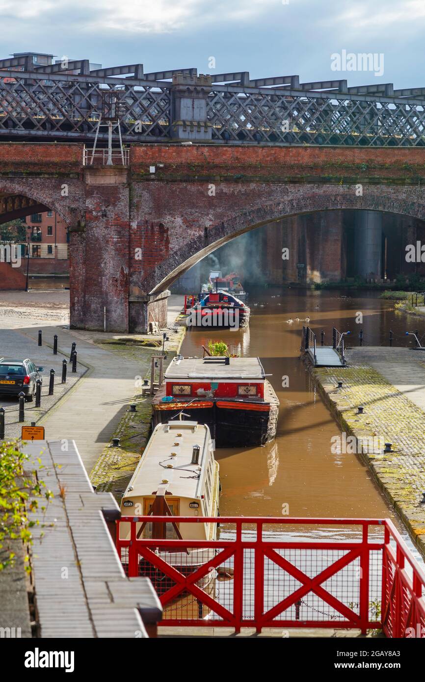 Barche strette ormeggiate dall'alzaia sul canale di Bridgewater da un viadotto ferroviario nel Castlefield Urban Heritage Park, Manchester, Inghilterra nord-occidentale, Regno Unito Foto Stock