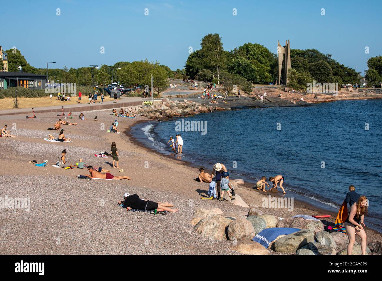 La gente prende il sole sulla spiaggia di Eiran ranta in una calda serata estiva nel quartiere di Eira a Helsinki, Finlandia Foto Stock