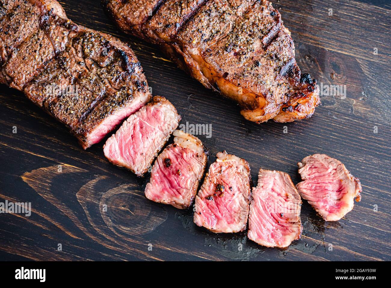 NY Strip Steak alla griglia con Coffee Rub: Bistecche alla griglia di New York Strip su sfondo di legno scuro Foto Stock