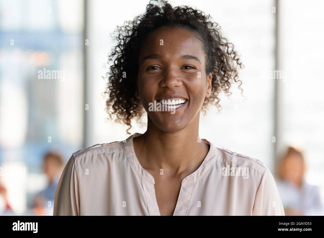 Gioiosa giovane donna d'affari africana che guarda la macchina fotografica. Foto Stock