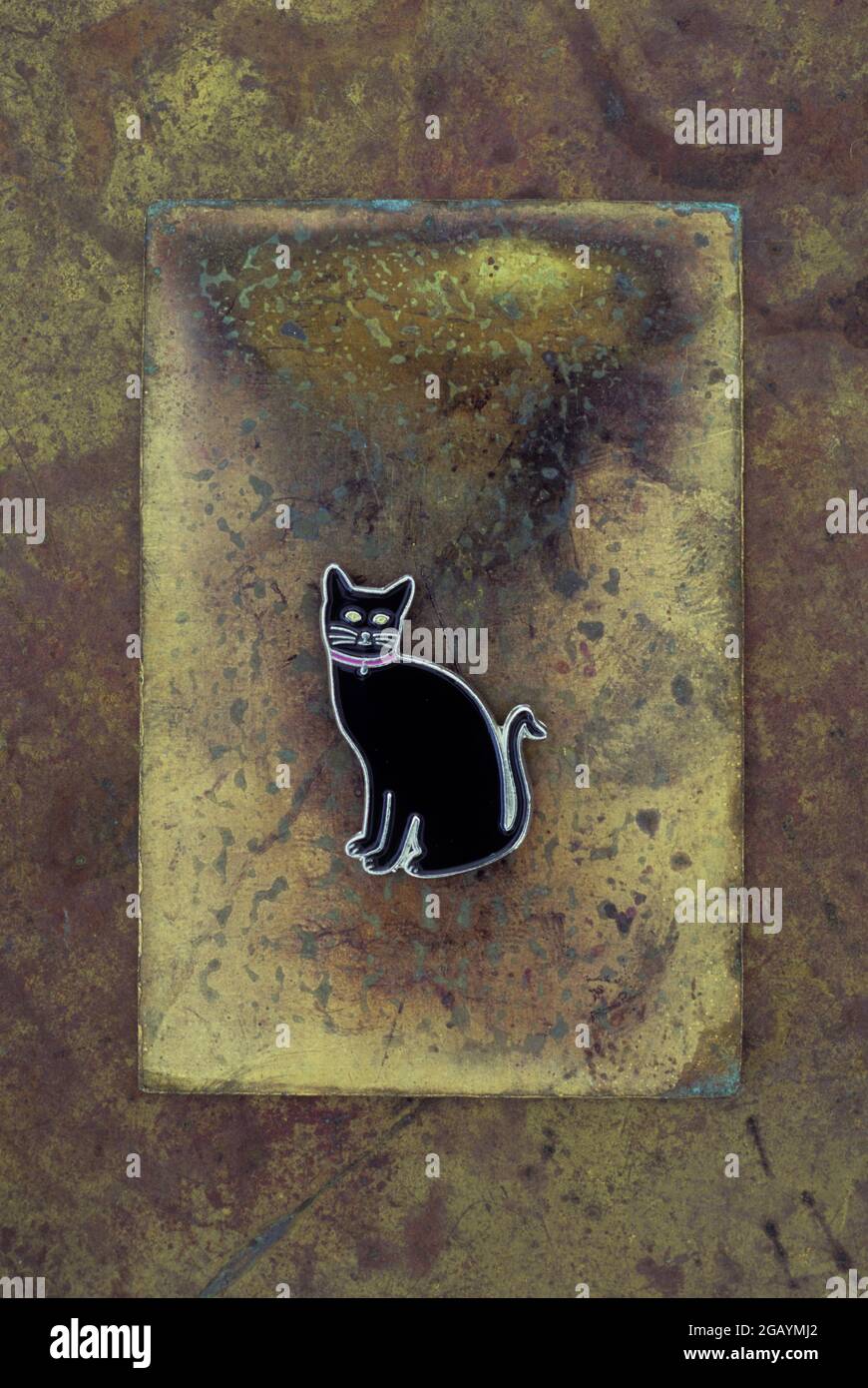 Spilla di smalto o badge o pin di gatto nero giacente su ottone brunito Foto Stock