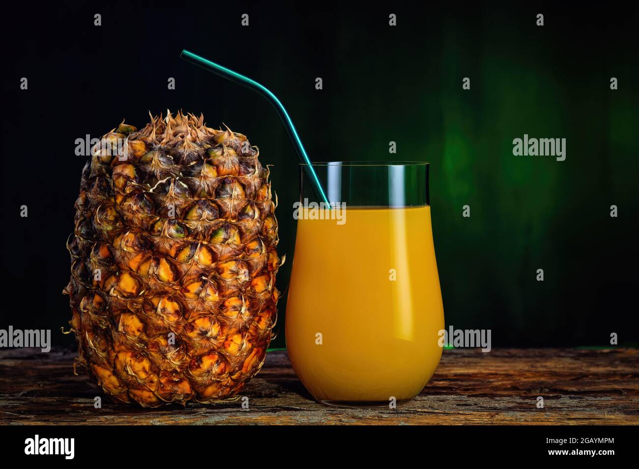 Succo di ananas fresco in un bicchiere e ananas fresco su sfondo verde scuro Foto Stock