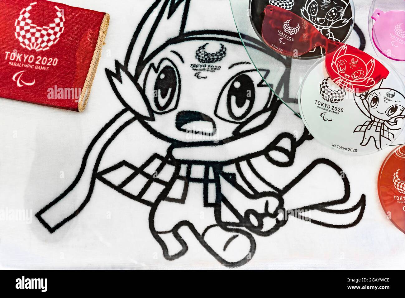 tokyo, giappone - luglio 20 2021: Closeup su asciugamano raffigurante ufficiale mascotte personaggio Someity incoraggiante con megafoni di plastica con altri beni correlati Foto Stock