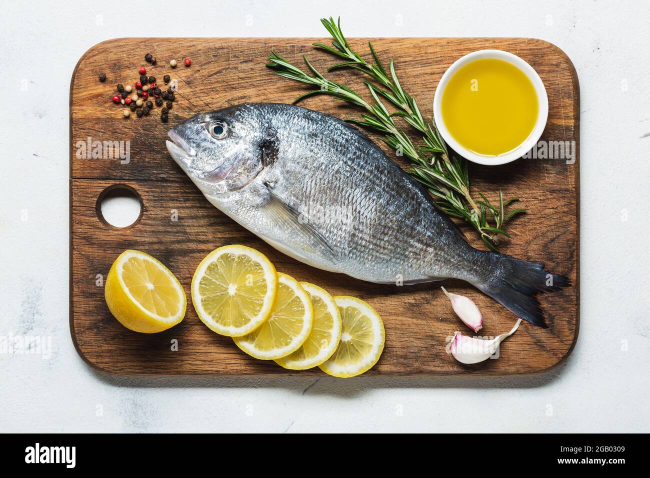 dorado fresco su un tagliere con limone e spezie preparati per la cottura. Vista dall'alto. Foto Stock