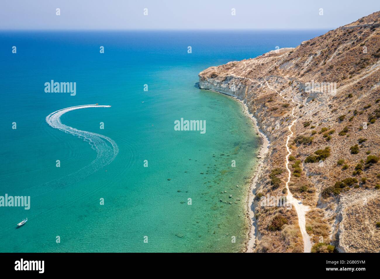 Barche a motore che lasciano il sentiero nella baia di Pissouri, Cipro con scogliere a forma di tartaruga gigante e Mar Mediterraneo sullo sfondo, mare marino aereo Foto Stock