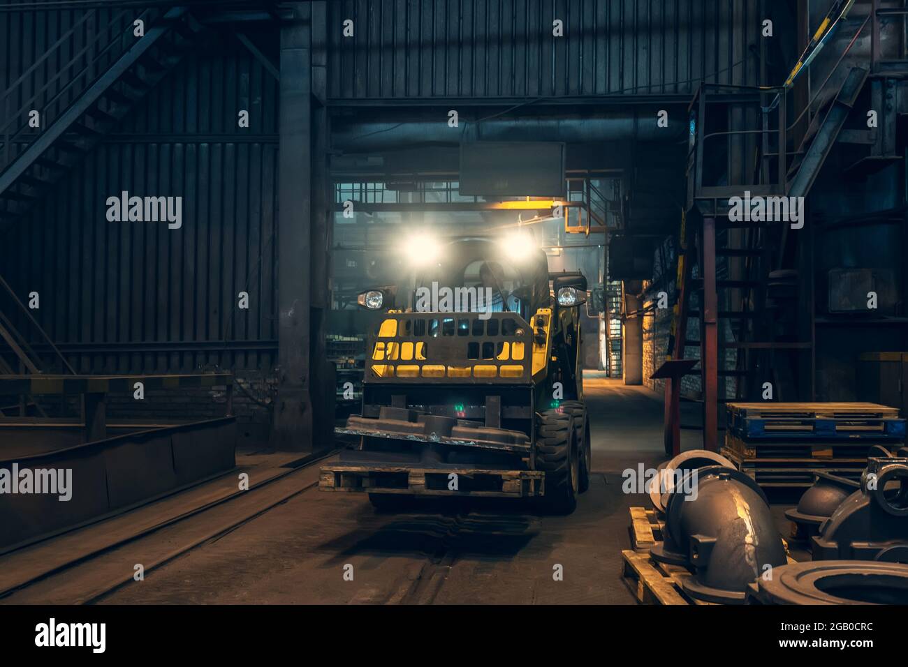Piccolo trattore giallo o falciatrice sul lavoro in officina di fabbrica metallurgica. Foto Stock