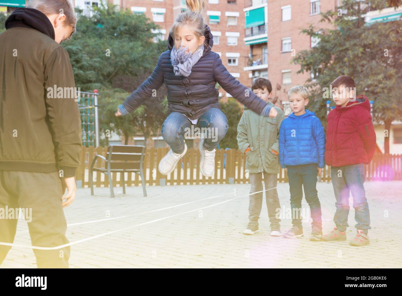 Kids saltando sul cinese il salto corda elastica in cantiere Foto Stock