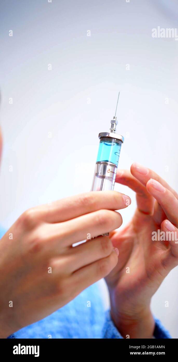 Una foto verticale delle mani di una donna che sta usando una siringa Foto Stock