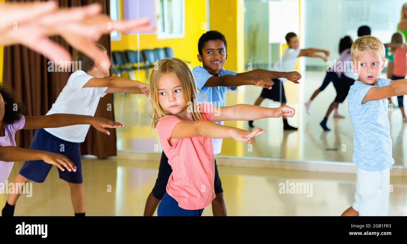 I ragazzi e le ragazze presteen praticano la danza, allungandosi con l'allenatore femminile nella sala da ballo Foto Stock