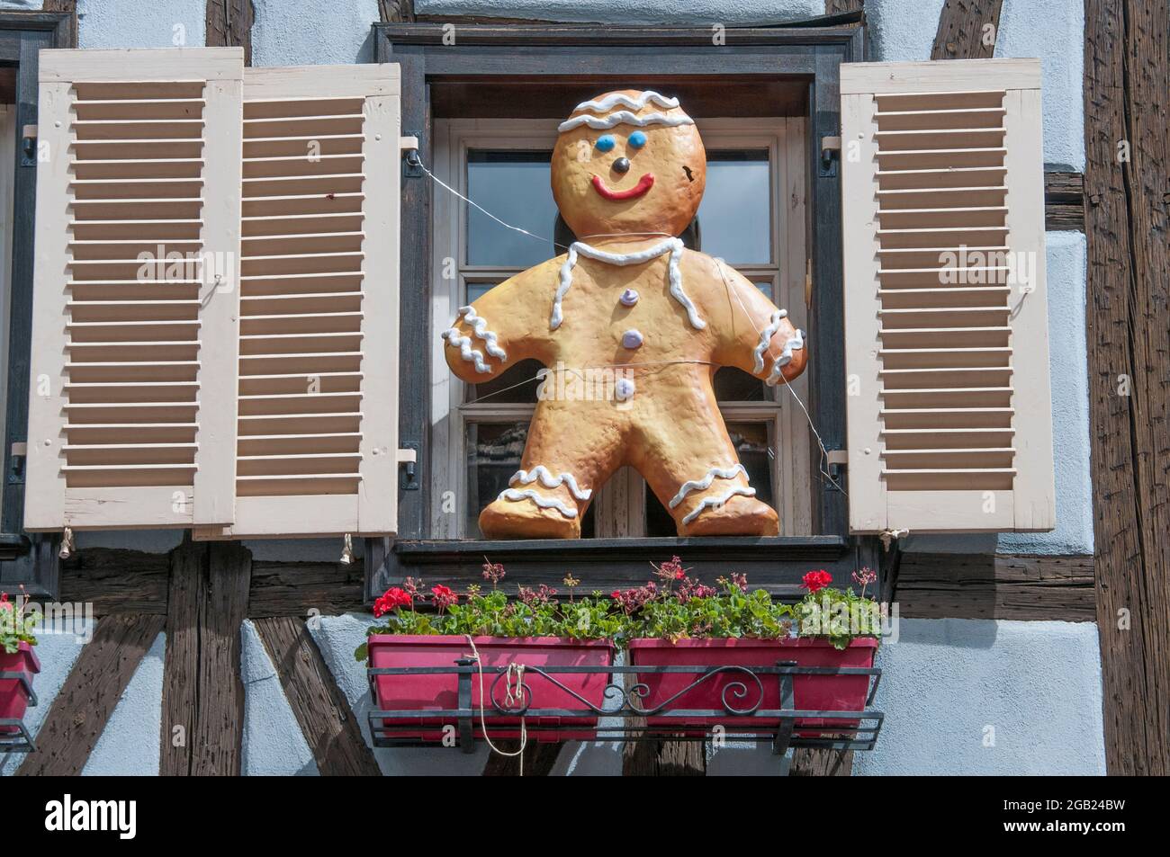 Una scultura di un uomo di pan di zenzero, simile a un bambino, adorna la finestra di una casa a graticcio a Kaysersberg, una città sulla strada del vino dell'Alsazia, nella Francia orientale Foto Stock