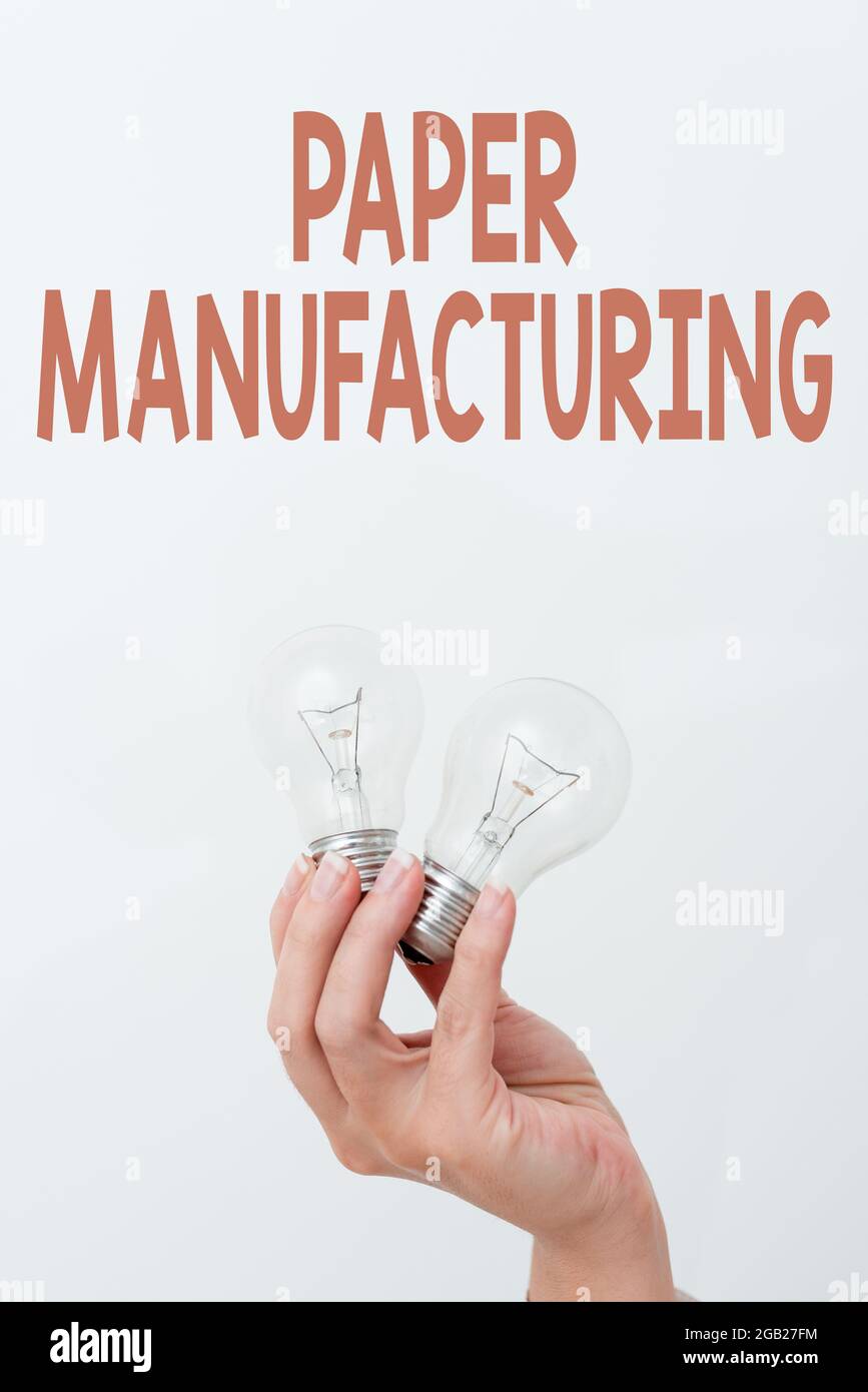 Scrittura a mano di testo produzione di carta. Internet Concept società che utilizzano il legno come materia prima e producono carta mano che tiene due lampada che mostra o. Foto Stock