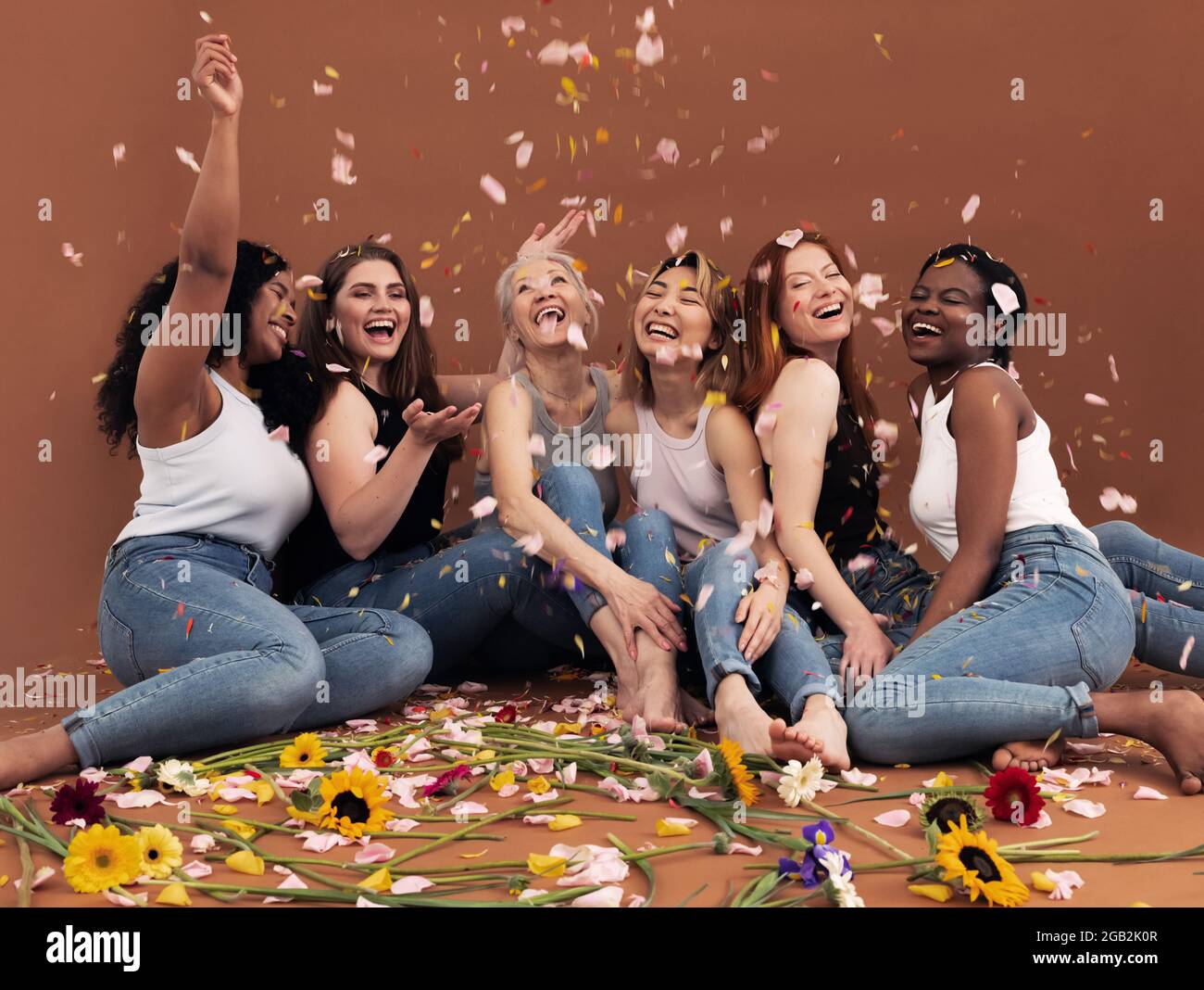 Gruppo multietnico di donne felici sotto i petali che cadono Foto Stock