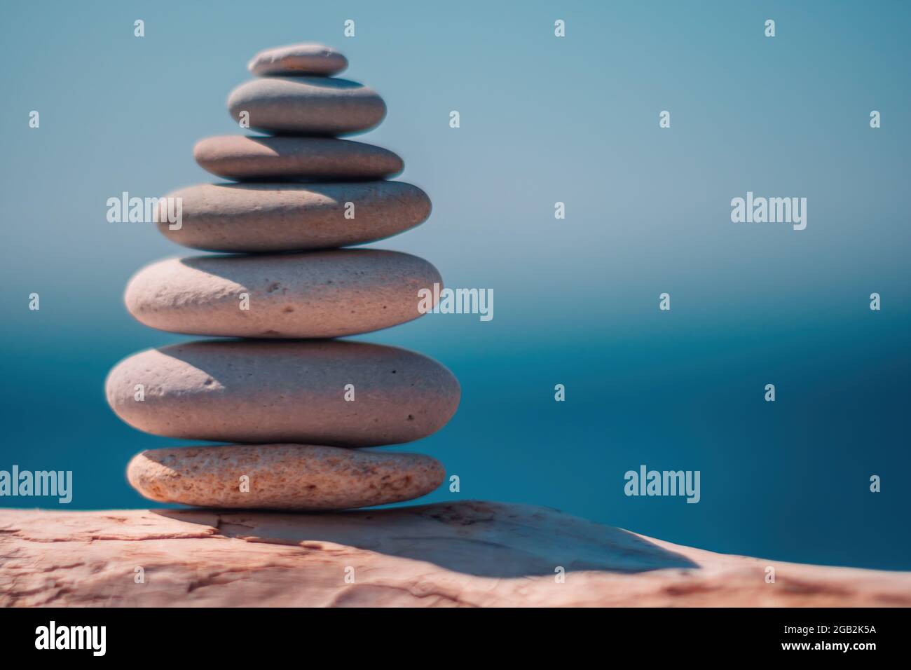 Equilibrata piramide di ciottoli sulla spiaggia in una giornata di sole. Abstract Sea bokeh sullo sfondo. Messa a fuoco selettiva. Pietre Zen sulla spiaggia di mare, meditazione Foto Stock
