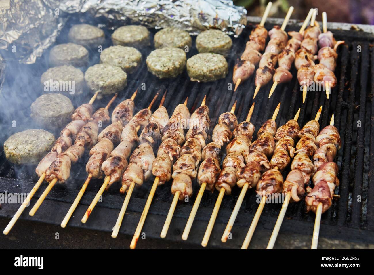 Hamburger al barbecue, cuori grigliati su spiedini e barbecue di fumo festa. Primo piano Foto Stock