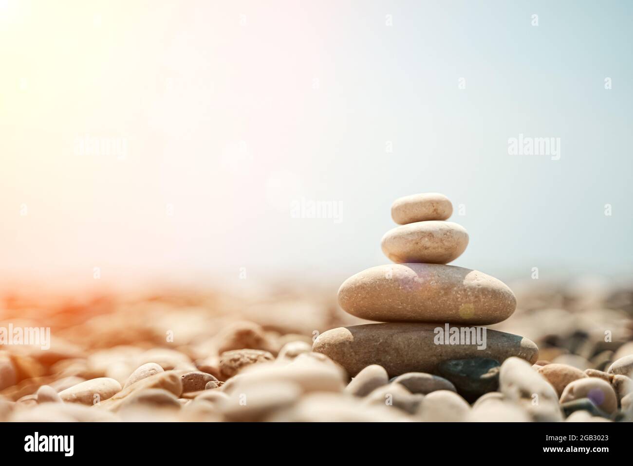 Pietre Zen sono sfondo. Una piramide di pietre di ciottoli sullo sfondo del cielo, del mare e della spiaggia. Meditazione, yoga, rilassare la mente e il concetto di relax. Foto di alta qualità Foto Stock
