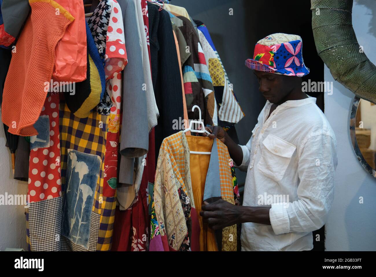 Uomo nero che sceglie un capo di abbigliamento africano da indossare. Foto Stock