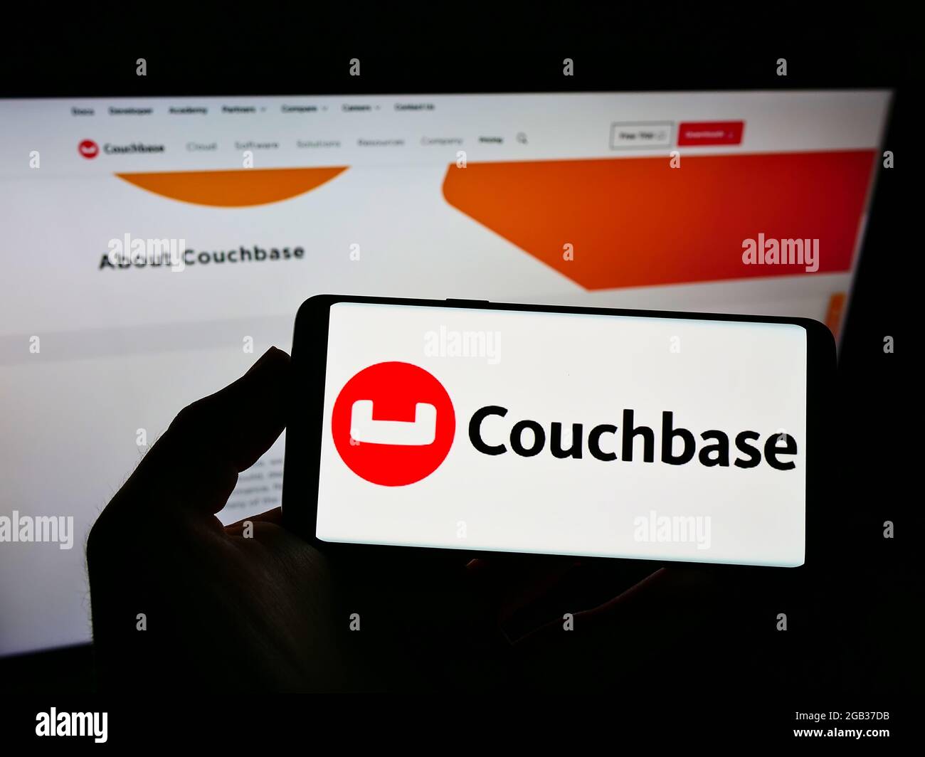 Persona che detiene smartphone con il logo della società di software statunitense Couchbase Inc. Sullo schermo davanti al sito Web. Mettere a fuoco il display del telefono. Foto Stock