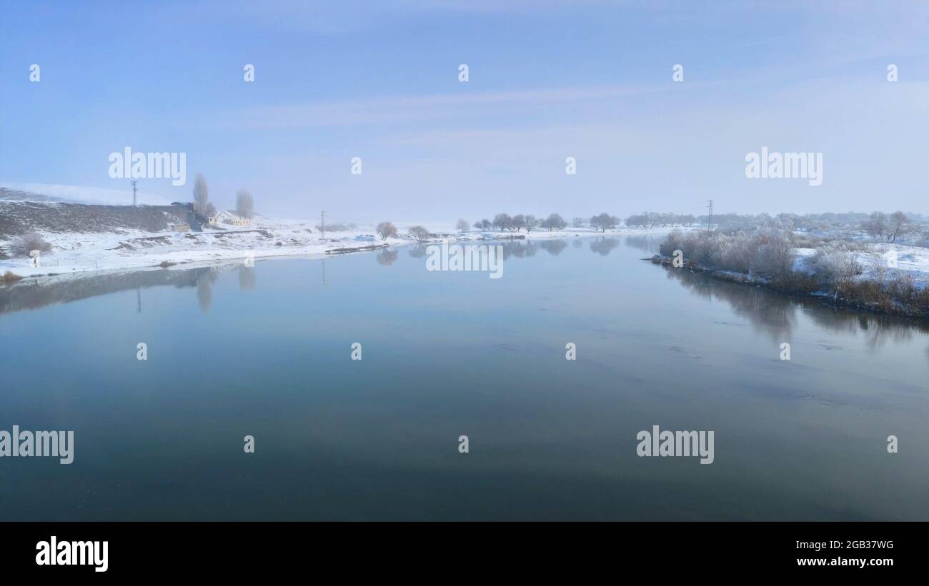 Fiume che scorre attraverso il paesaggio invernale. Alberi coperti di brina. Foto Stock