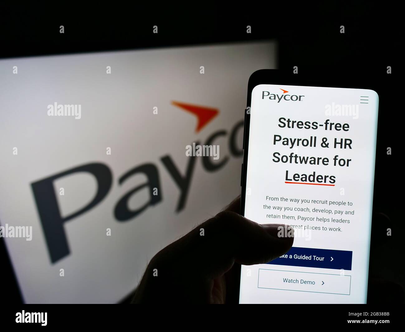Persona che detiene il telefono cellulare con la pagina web della società di software HR USA Paycor HCM Inc. Sullo schermo davanti al logo. Mettere a fuoco il centro del display del telefono. Foto Stock