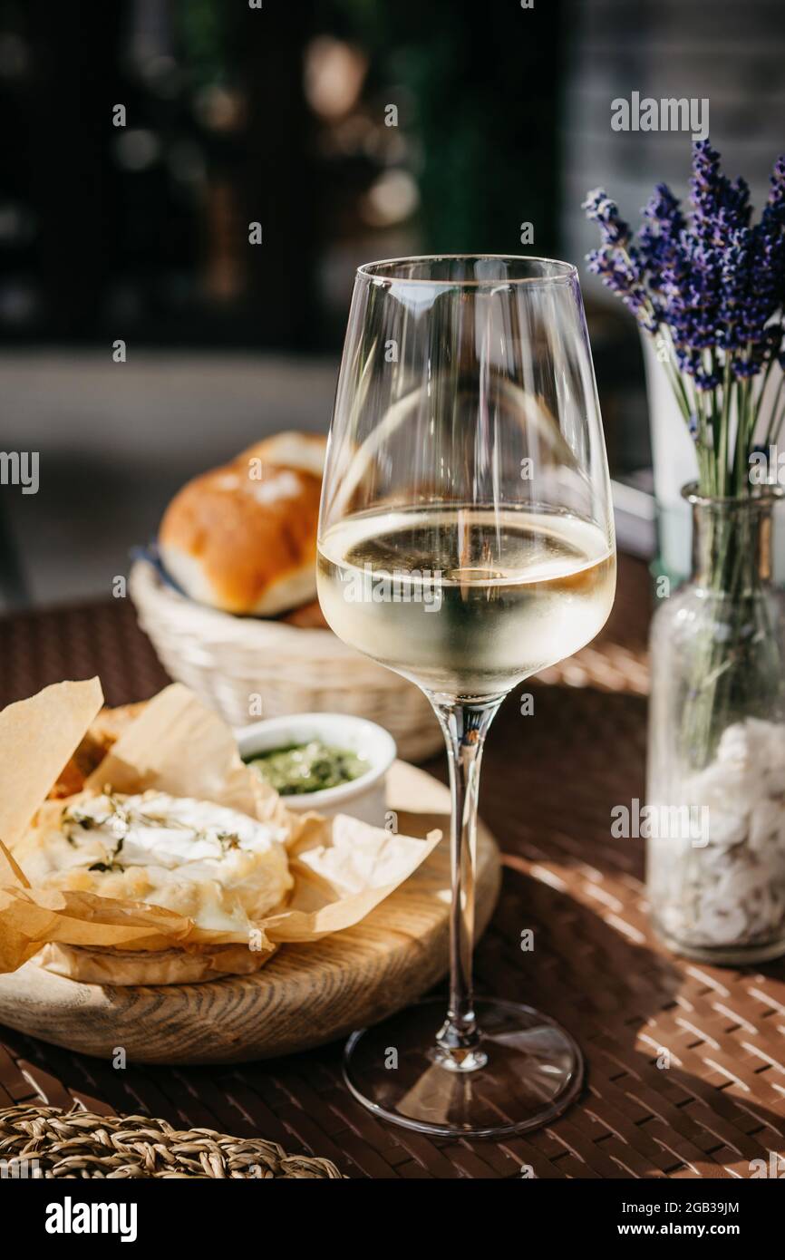 Bicchiere di vino bianco freddo e formaggio camembert al forno Foto Stock