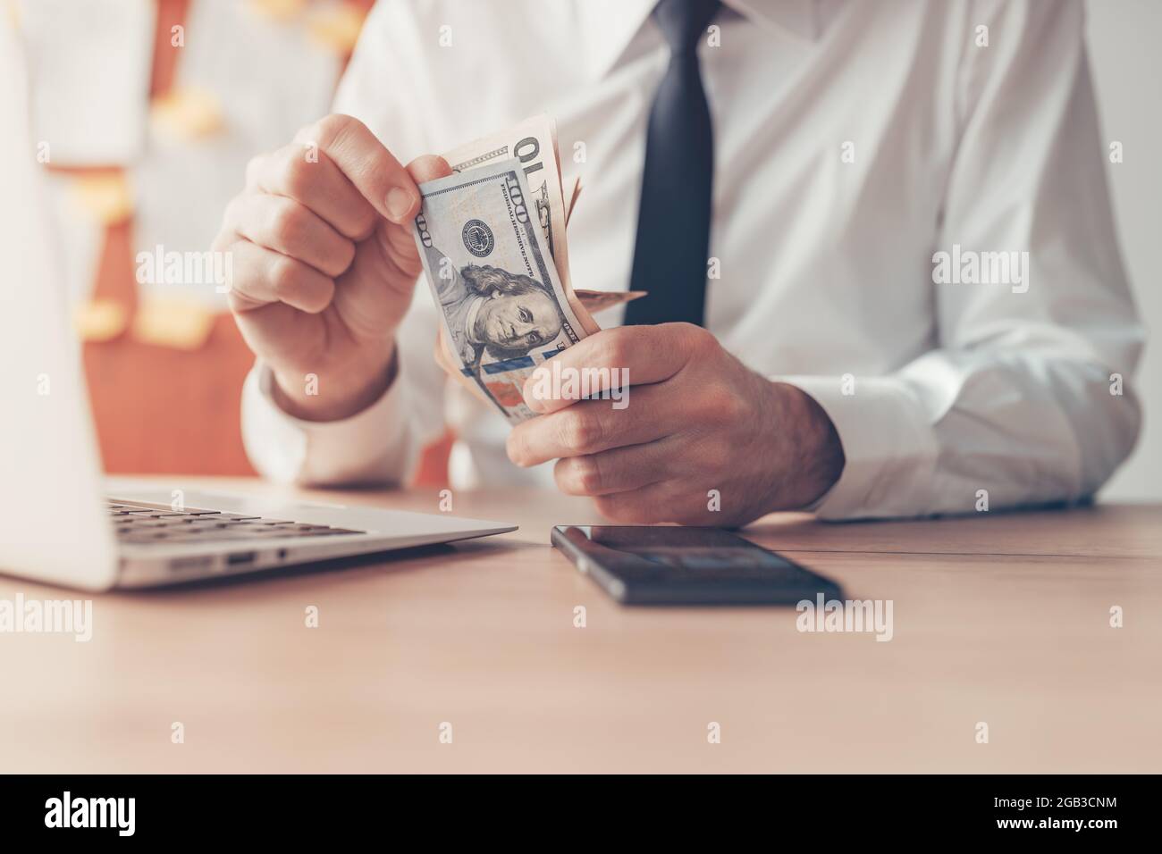 Fatturato aziendale, imprenditore che conta denaro contante in dollari USA in ufficio, primo piano con focus selettivo Foto Stock